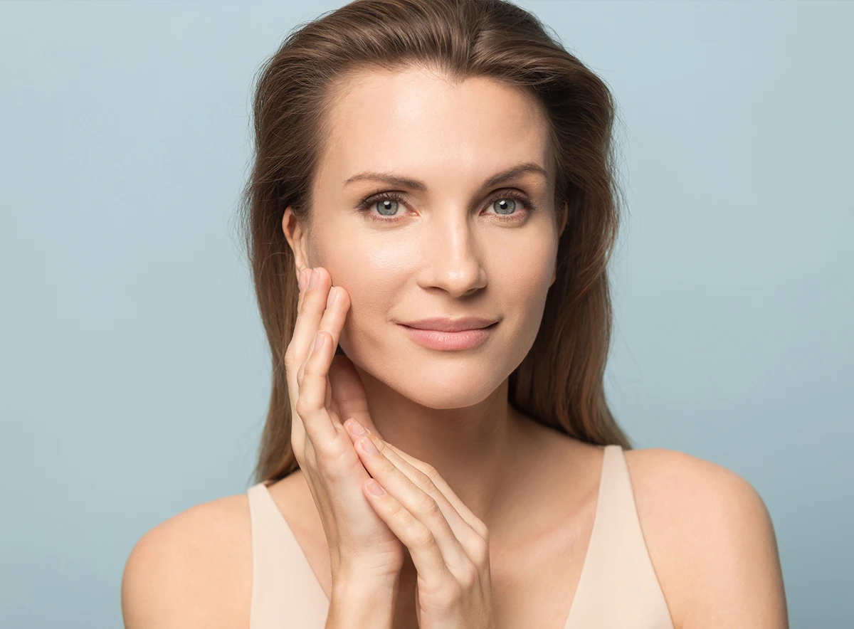 Facial Plastic Surgery Gulf Shores: Woman touching cheek with smooth skin and balanced features